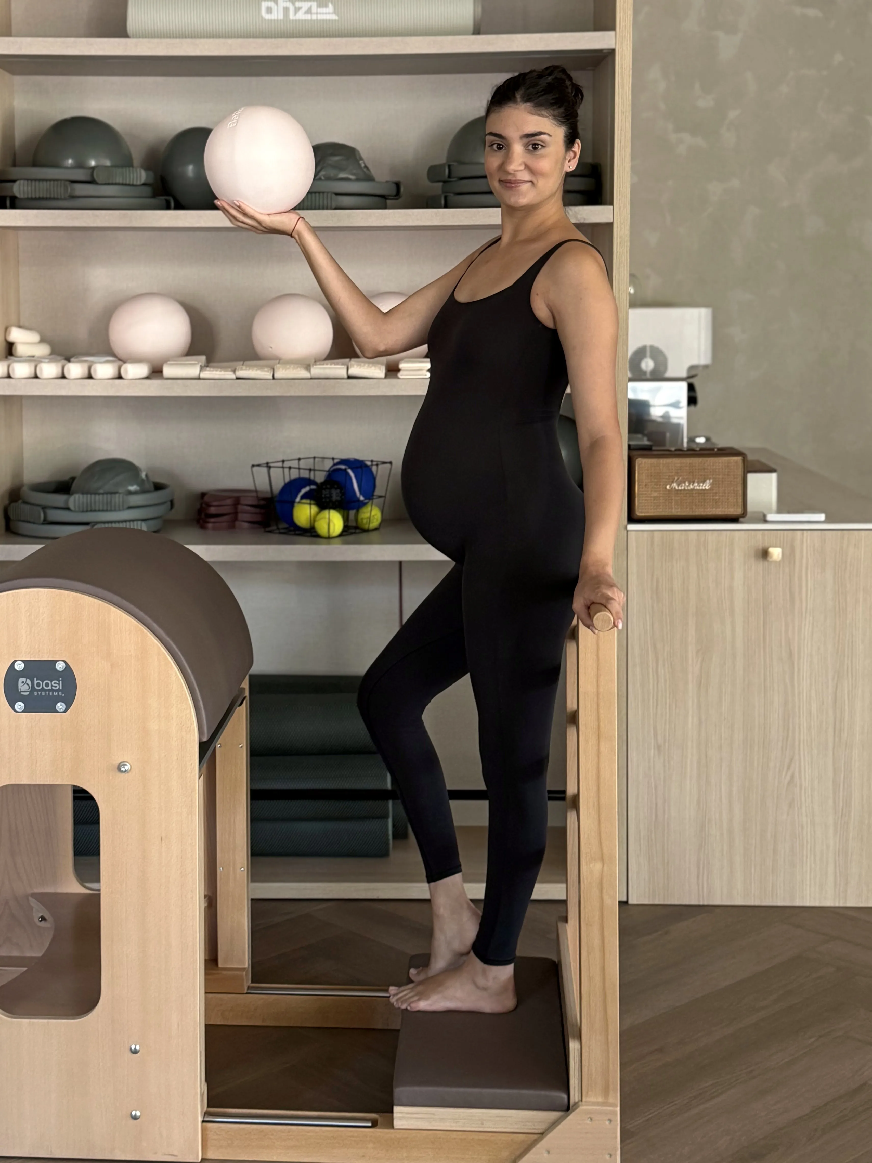 Femeie însărcinată în studio, cu o minge Pilates în mână